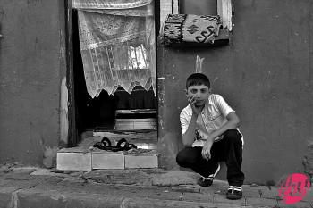 Un bambino davanti alla porta della sua abitazione. Istanbul, Turchia